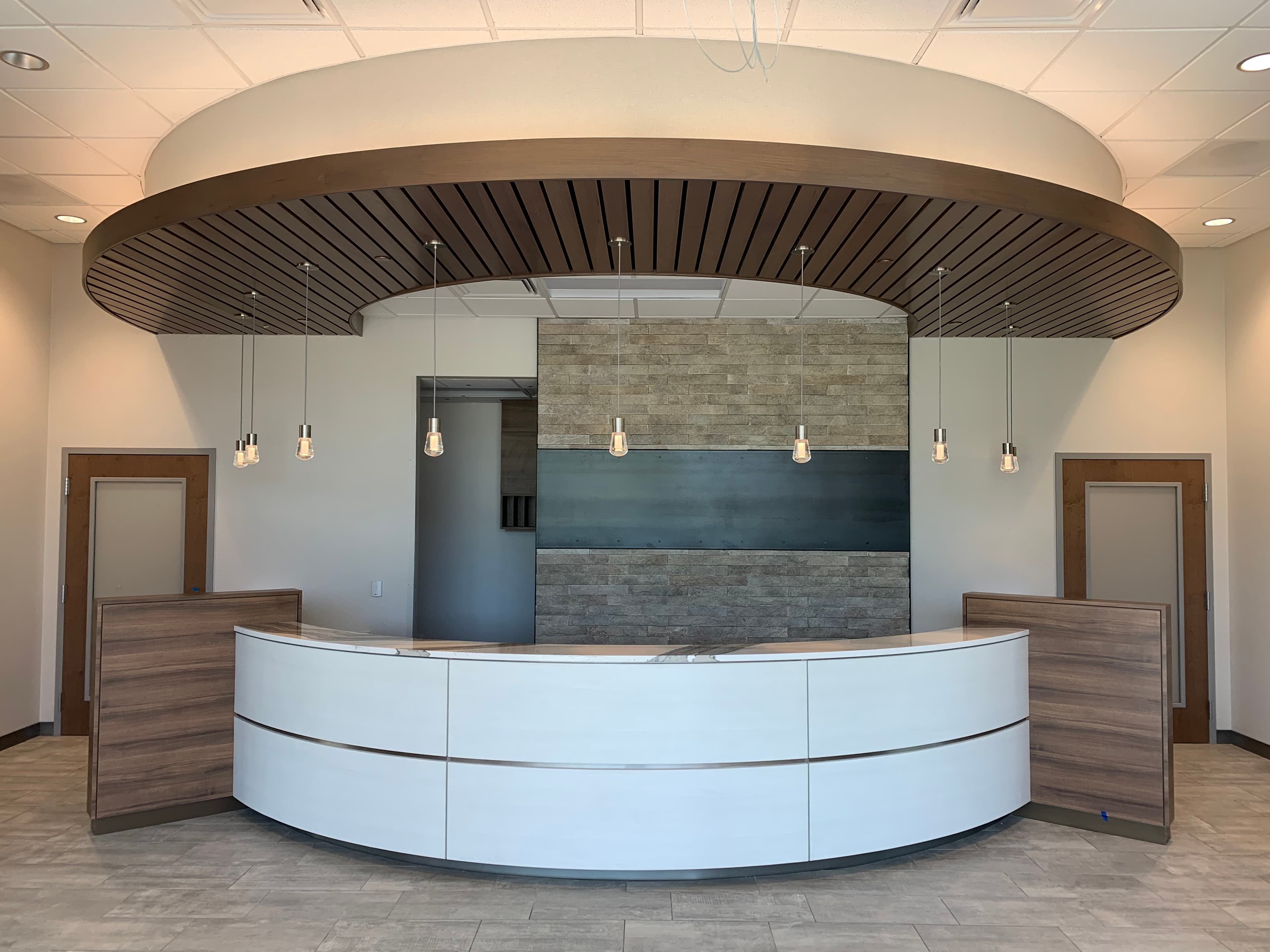 Curved reception desk with wood end panels under a round slatted wood canopy